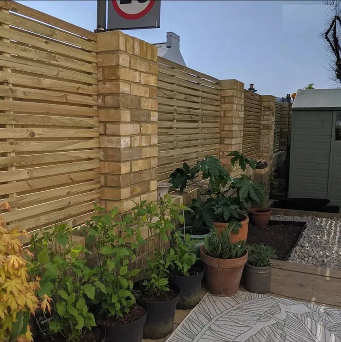 Bespoke made slatted timber fence panels set between extended brick piers in Petts Wood