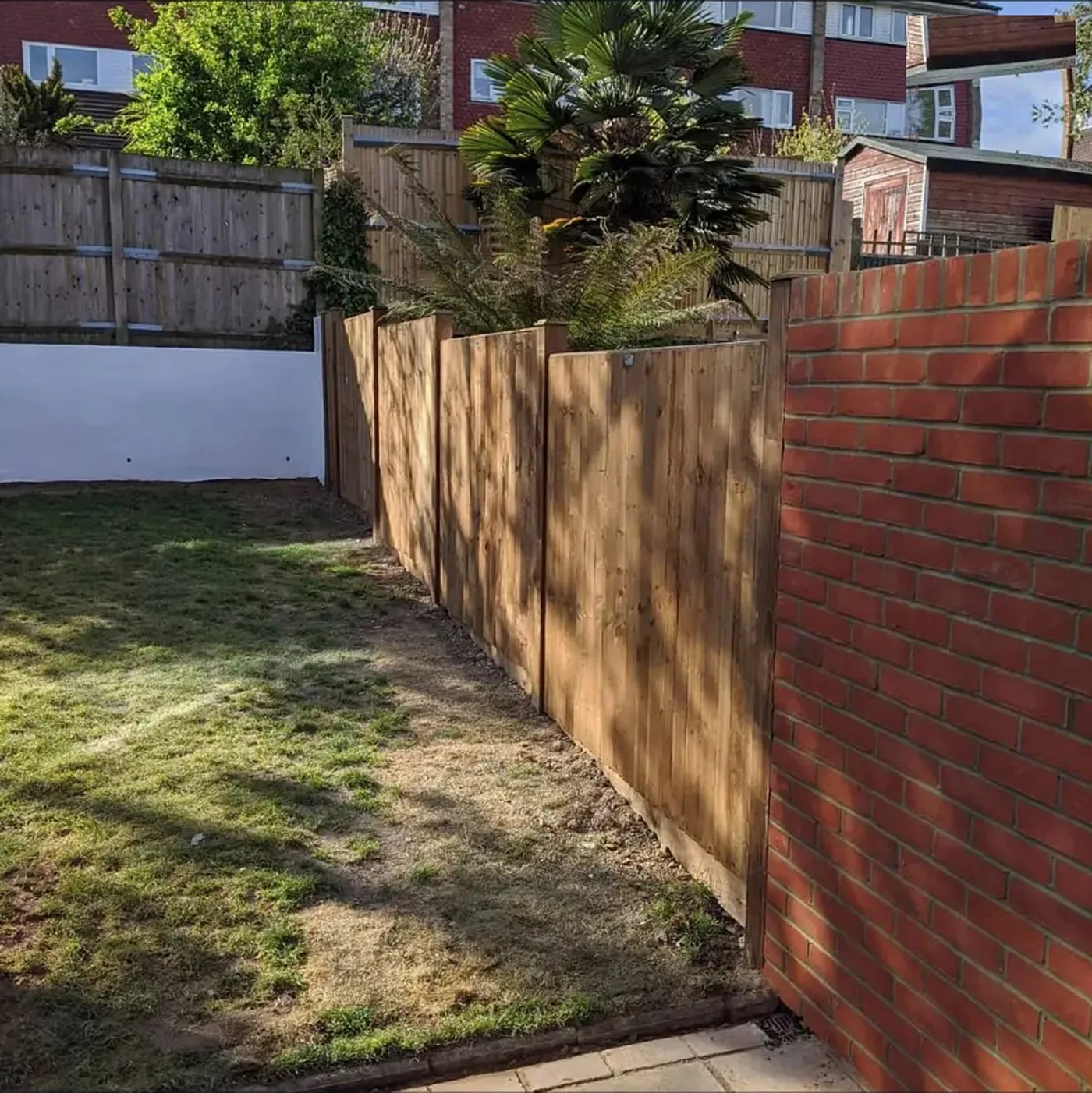 Feather edged close board fence with concrete posts running alongside a nine inch brick garden wall in Bromley